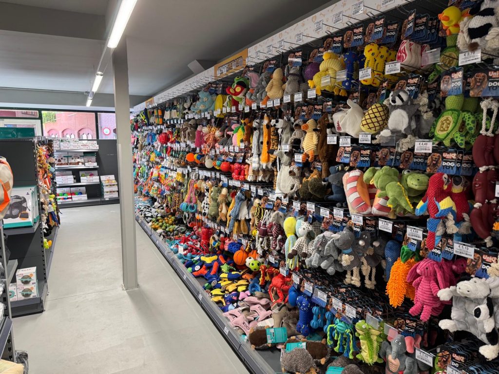 Winkelrek vol gekleurde speelgoedbeesten en knuffelkat toys met prijskaartjes in een diervoedingwinkel.