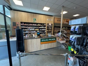 Interieur van een dierenwinkel met houten balie, metalen stellingen met producten, en displayrekken met diervoeding en accessoires.