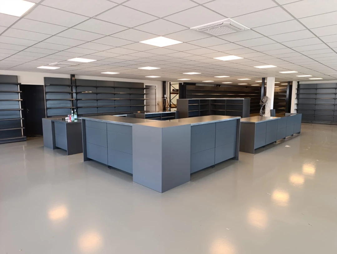 Leeg winkelinterieur met blauwe verkoofsbalies, zwarte stellingkasten en moderne plafondverlichting.