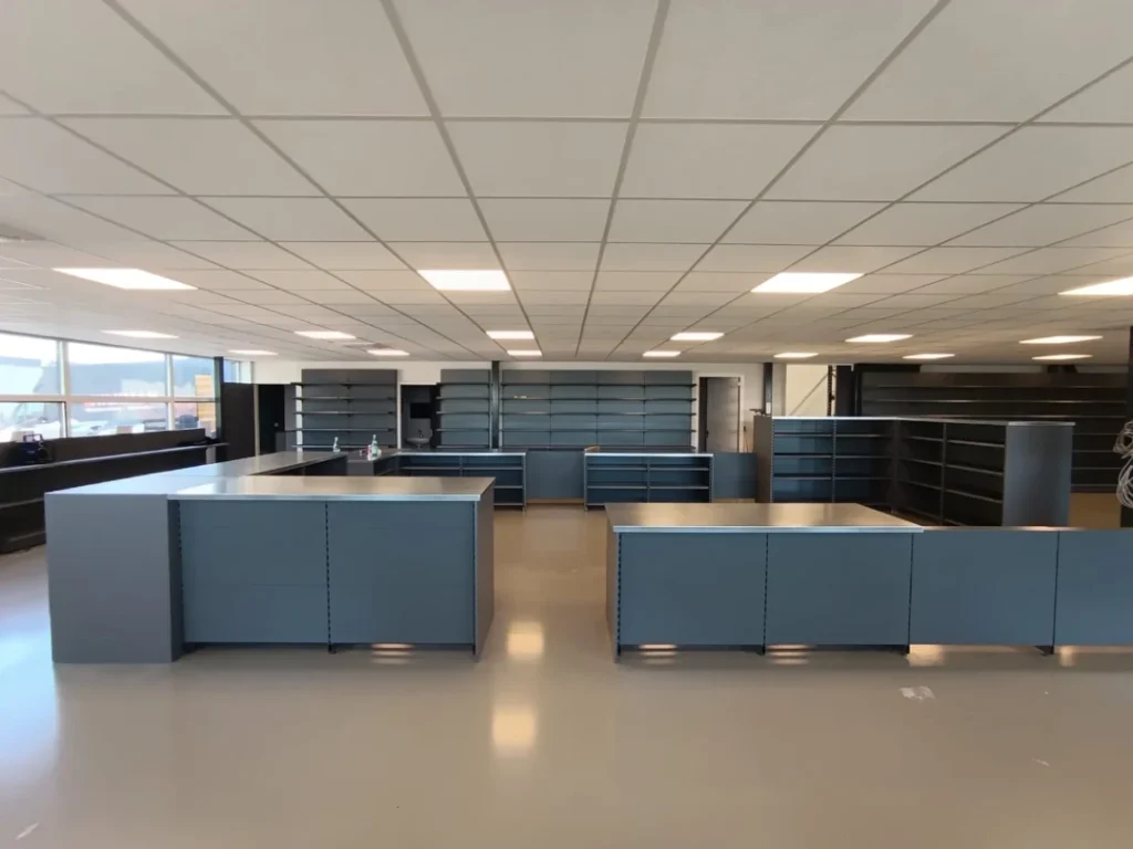 Leeg winkelinterieur met grijze metalen stellingen, balies en vitrinekassen onder plafondverlichting.